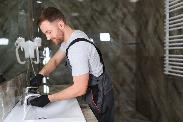 Ein Handwerker verschraubt eine Armatur